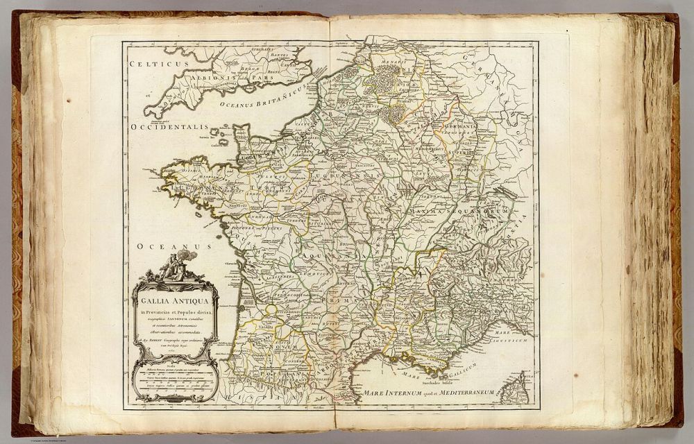 Carte ancienne colorée de la Gaule ouverte dans un atlas relié, avec cartouche décoratif et noms latins des peuples